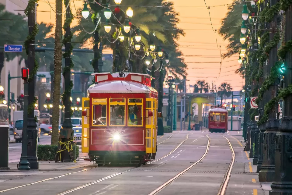 Red and yellow New Orleans streetcar running down street lined with palm trees